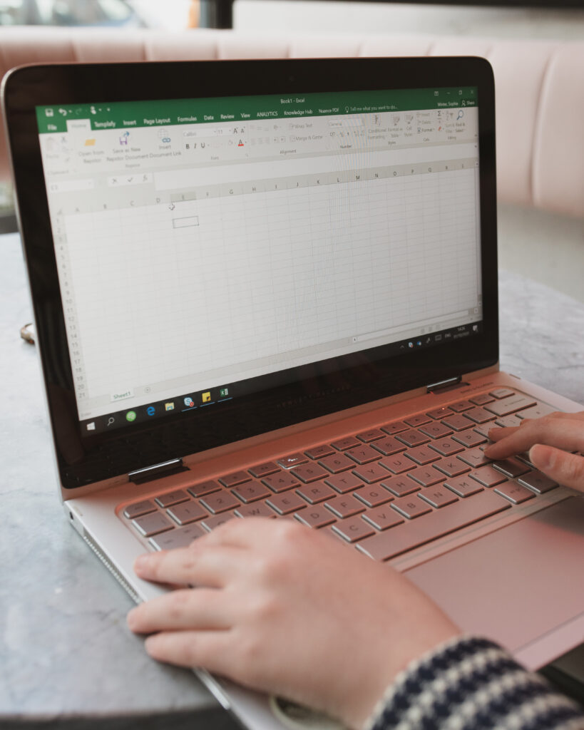 Image of Sophie typing on a silver HP laptop in Excel to show that it is important to ask what a day in the job role looks like in a job interview